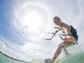 A young woman kiteboards under the sun.
