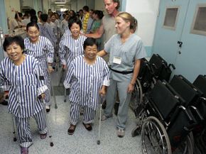 Patients suffering from bone diseases walk with the help of nurses and U.S. volunteers after undergoing joint replacement surgeries at the West China Hospital of Sichuan University.
