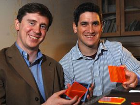 麻省理工学院副教授Marc Baldo(左)和博士后学生Shalom Goffri正在展示一些有机太阳能聚光器。”width=