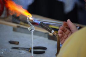 Lampworkers use a torch to heat the glass up enough to be able to work with it.