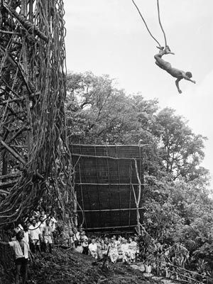 Men outdoors in black and white, rope in hand.