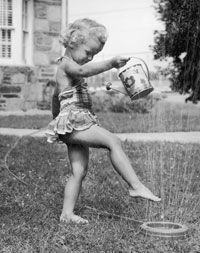Little girl plays in sprinkler, circa 1945.