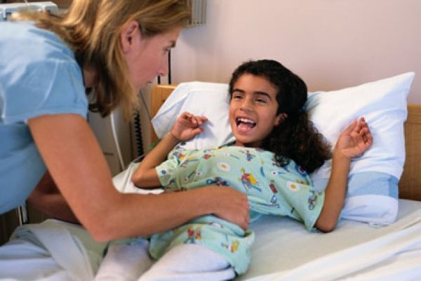 Two people smiling in a child's bedroom, on a bed.