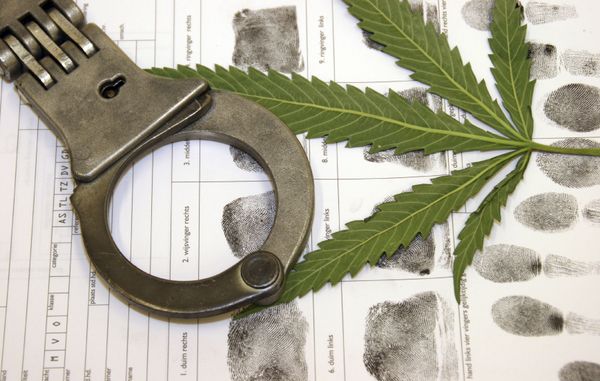 Marijuana and handcuffs on a booking form with fingerprints.