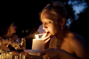 A woman lights her cigarette with a candle. 