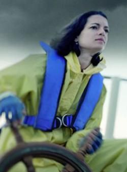 A woman wearing an inflatable life jacket navigates in a storm