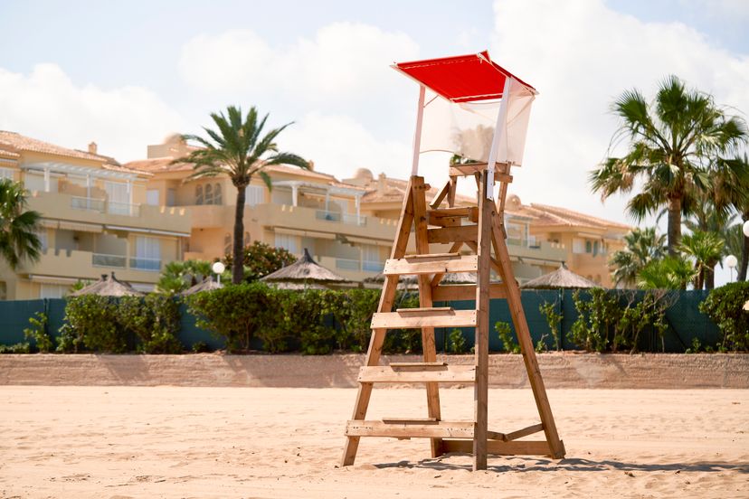 close-up photo of a single wooden Baywatch box with a red roof and in the background the hotel complex