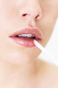 Macro of a young woman applying gloss