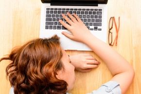 A woman sleeps on her desk.