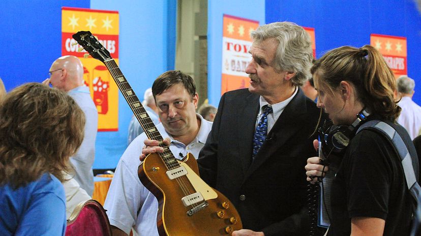 Richard Johnston, musical instruments appraiser for 'Antiques Roadshow' holds a 1955 Les Paul guitar brought for appraisal by Dan Sillaman (white shirt in background). Sillaman and his guitar were selected to be filmed for a later airing of the show.
 Tracy A Woodward/The Washington Post via Getty Images