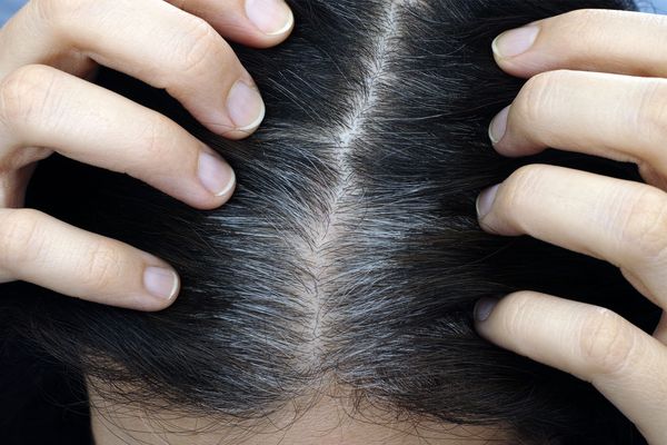 A person inspecting their gray hairs.