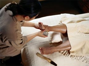 Man using pumice stone on person's foot