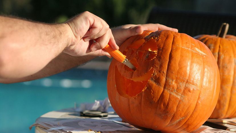 man's arm carving pumpkin