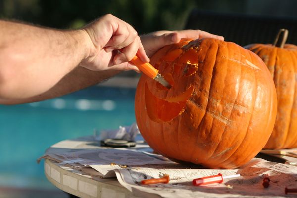 Man's arm carving pumpkin