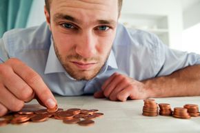 Unhappy young man in a collared shirt looking at a pile of pennies.