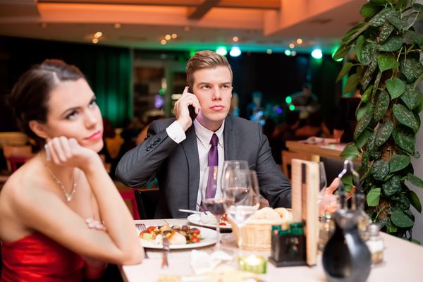 A woman bothered by her date answering his phone at the dinner table.