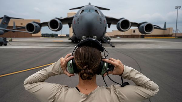 Men in armed forces flying air vehicle in military airplane.