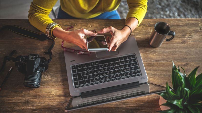 woman with smartphone, camera and laptop