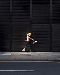 Photograph of running woman in mid-stride on a sidewalk.