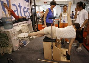 A woman in Beijing tries to figure out a Pilates exercise machine at a fitness expo.