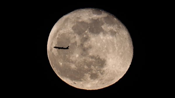 A passenger plane passes in front of the Full Pink moon as rises over Manhattan in New York City, United States on April 17, 2022.