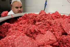 Ground beef passes through a machine at a meat packing and distribution facility.