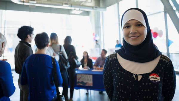 Women smiling in hijabs indoors.