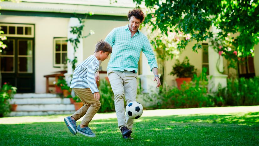 Full length of father and son playing soccer in lawn