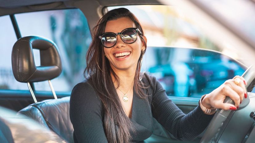 Happy brunette woman driving a car