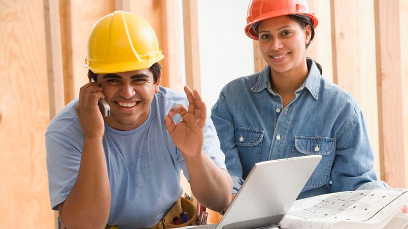 Construction workers gesturing okay while talking on cell phone