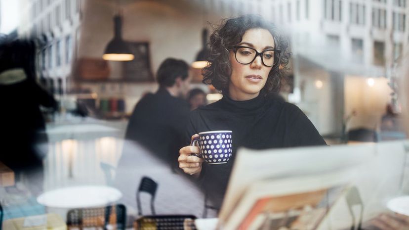 Woman Reading Newspaper at Coffee Shop