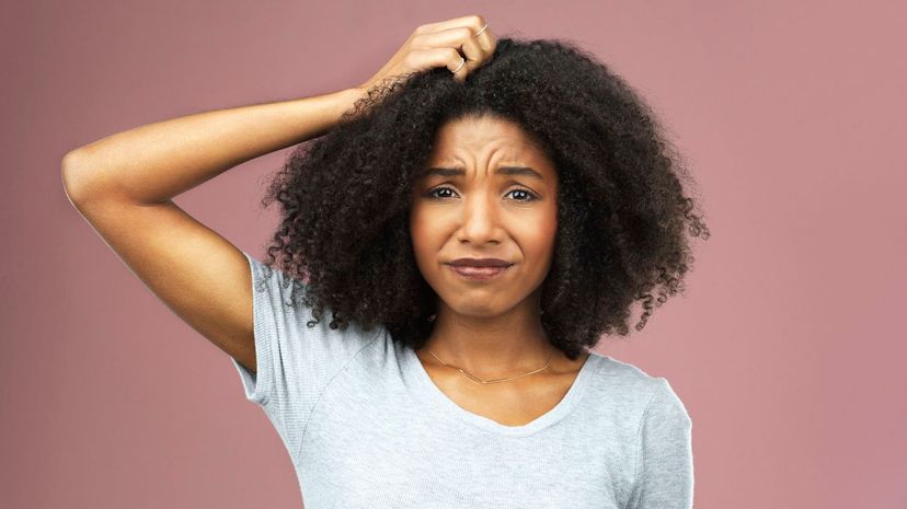 Frowned woman scratching head