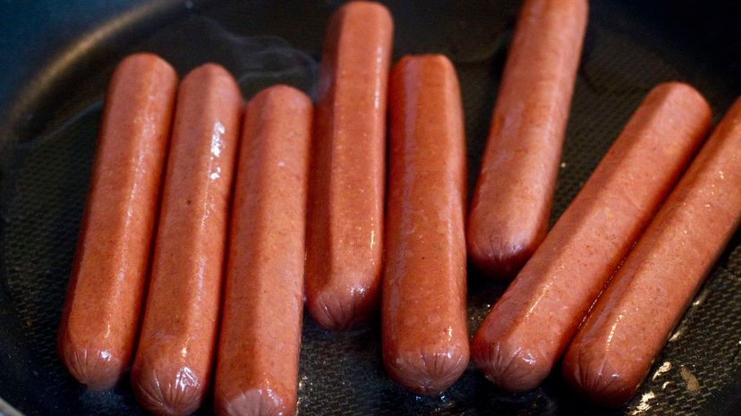 Hot dogs frying in pan