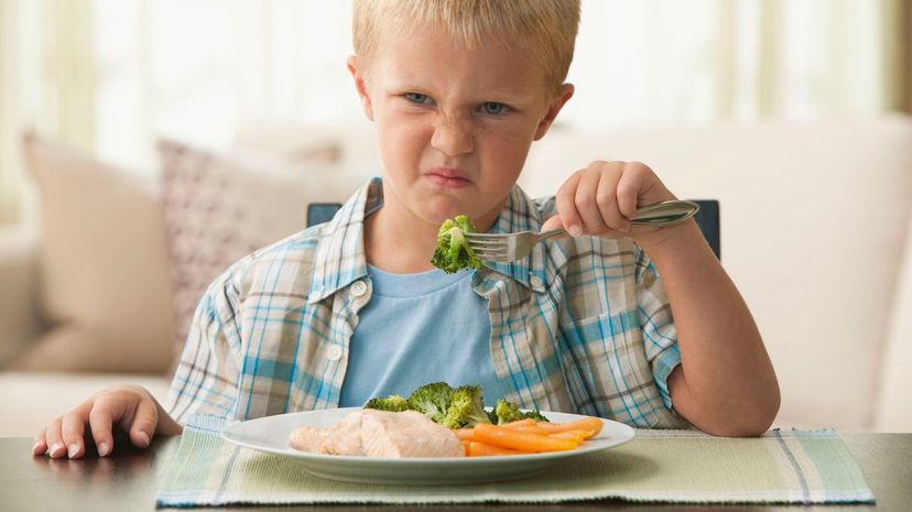 Unhappy boy eating vegetables
