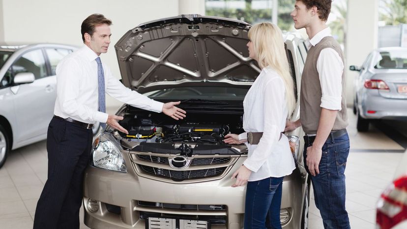 Car salesman showing engine to customers