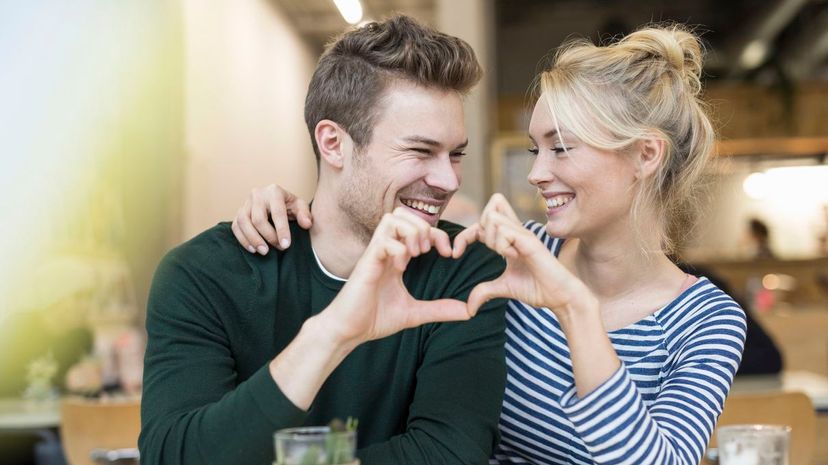 Couple making heart hands together in cafe