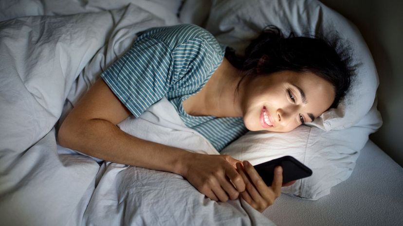 Woman checking her phone before going to bed