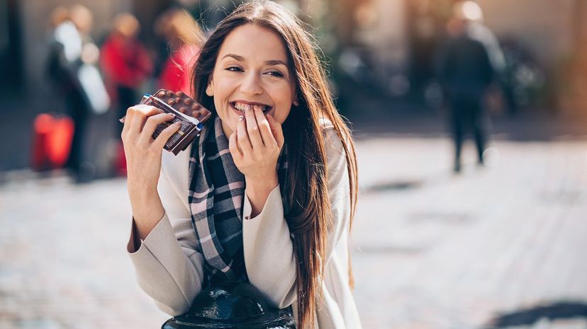 young businesswoman eating chocolate outdoors