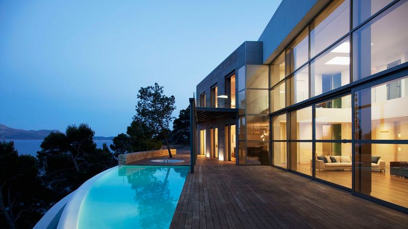 Pool outside modern house with glass wall at twilight