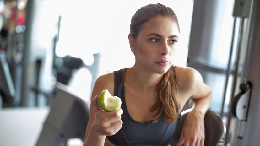 Woman eating apple in gym