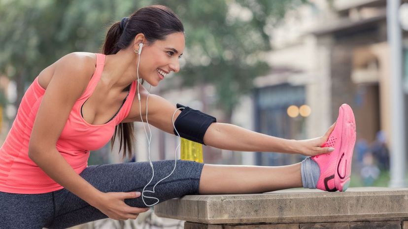 Young woman stretches legs before morning run