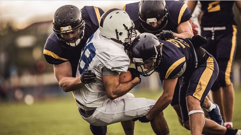 American football players tackling opposite's team quarterback