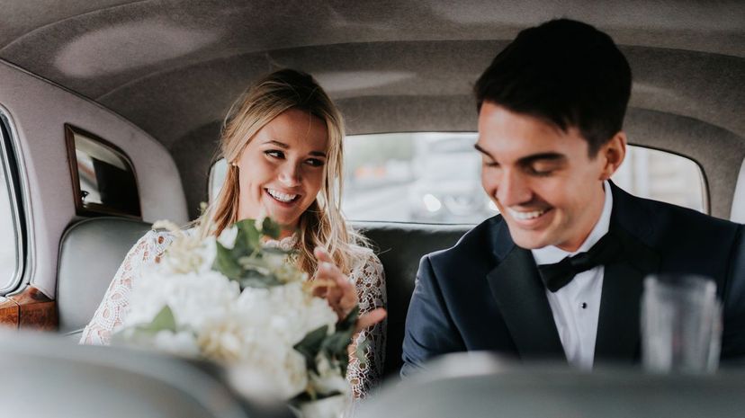 Bride and bridegroom in backseat of car