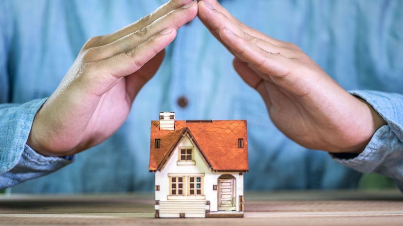 Hands covering a toy house