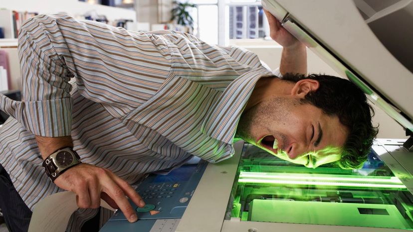 Male office worker photocopying side of face