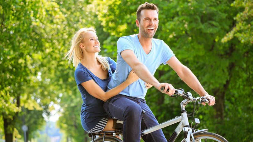 Happy couple in a park riding bike