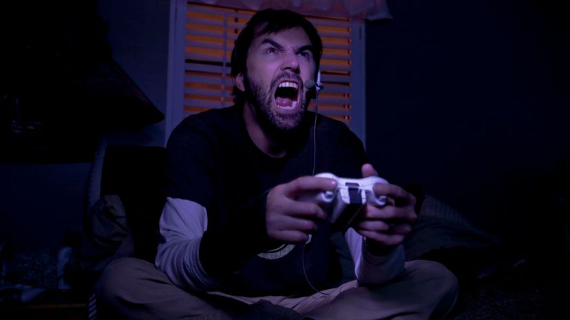 Mid adult man shouting whilst playing video game at night
