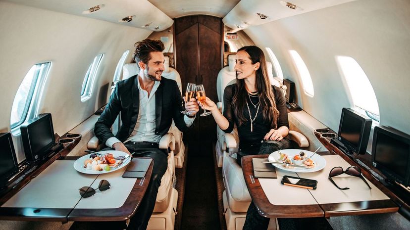 Successful couple making a toast with champagne glasses in a private airplane