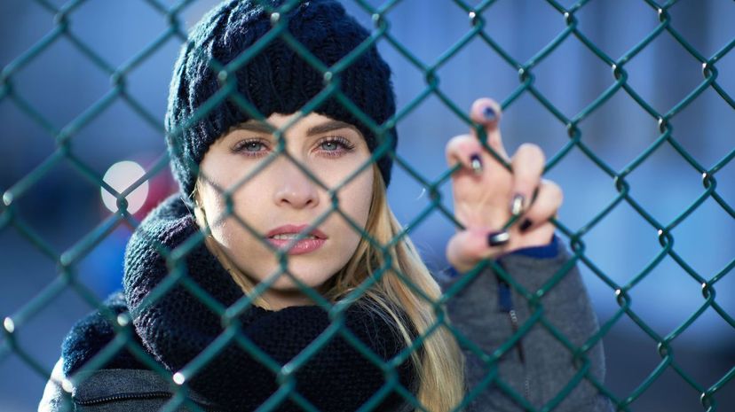 Woman stands behind fence