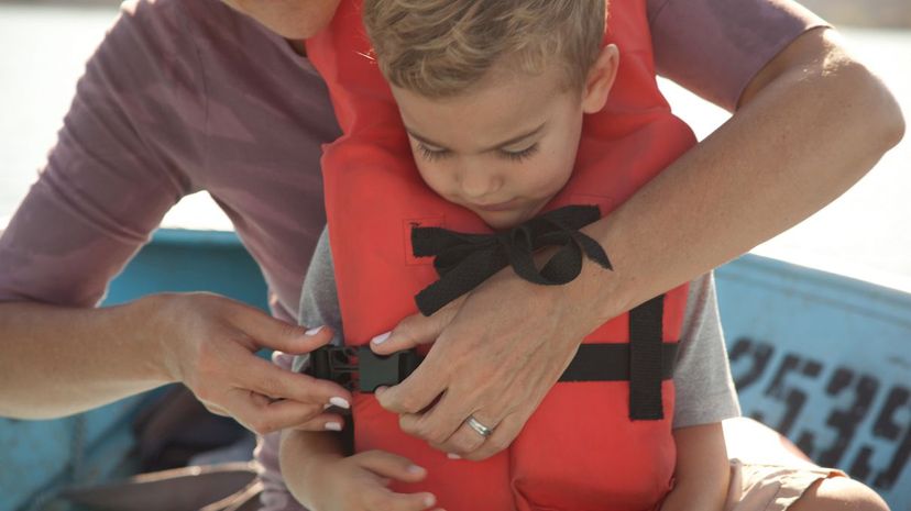 Mother fastening son's life jacket